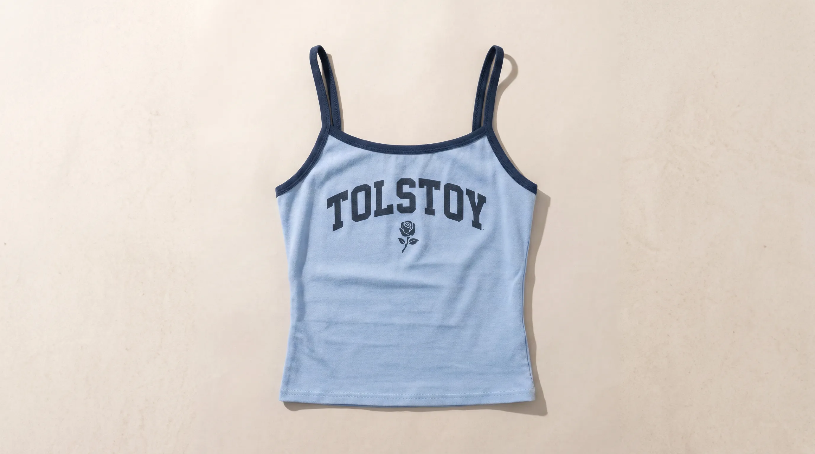 Centered product flat lay of the same light blue Tolstoy tank on a warm stone surface